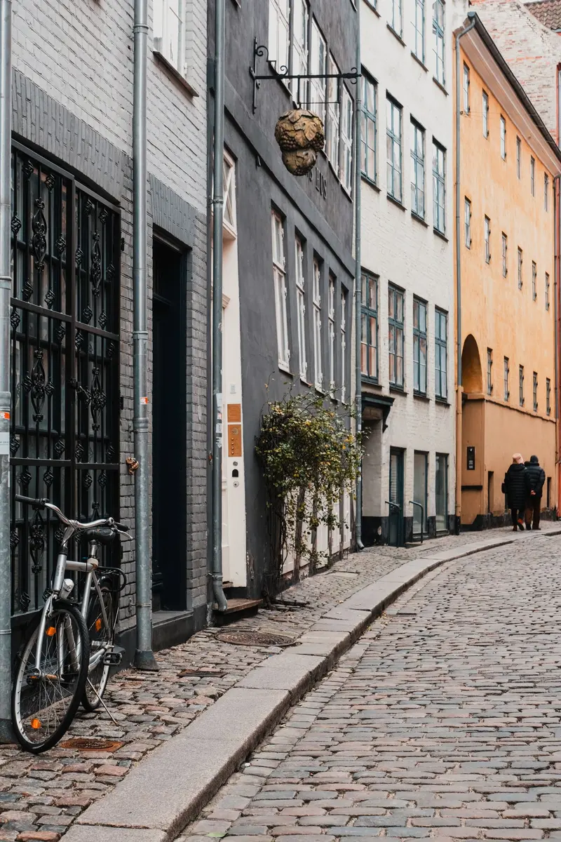Parkeringsområde ved dansk bygade med brostensbelægning.